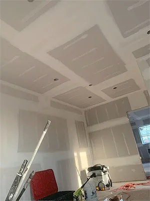 A professional transitioning a plaster wall to a smooth drywall finish.