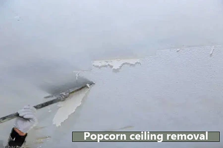 A professional worker removing popcorn ceiling texture using specialized tools in a well-prepared, clean interior space.