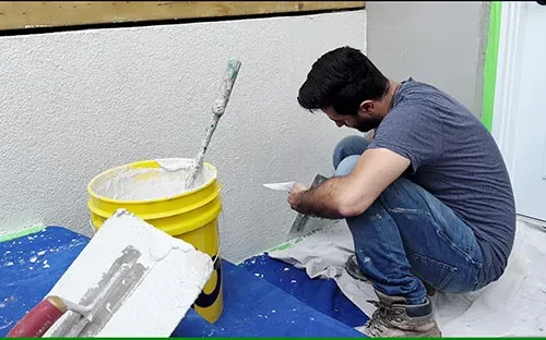 Professional worker applying stucco to a residential exterior wall using a trowel for a smooth and durable finish